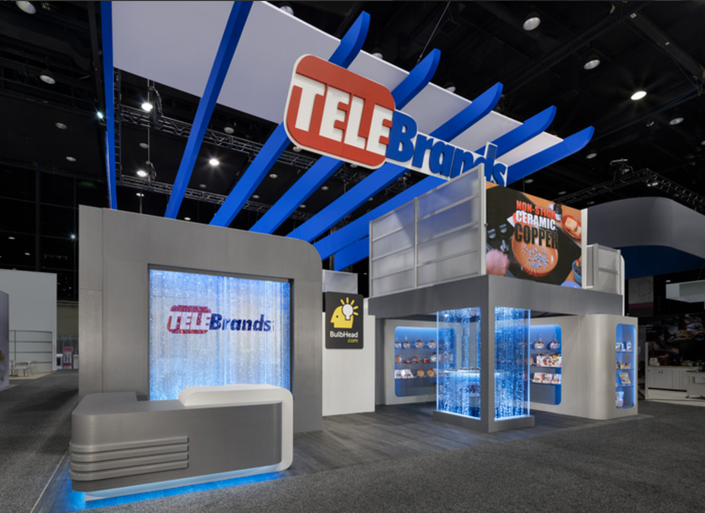 TeleBrands exhibition booth with its overhead logo, blue illuminated displays and product showcases